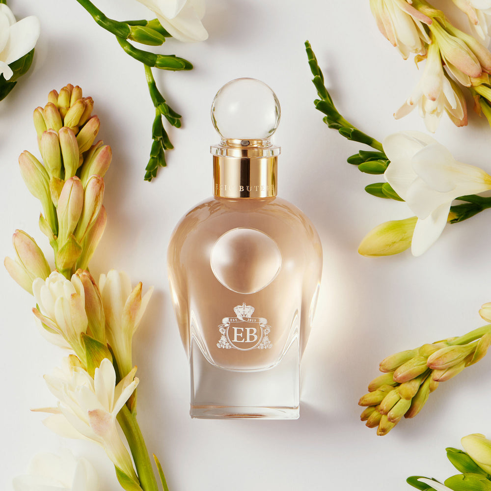 A 100 ml Regal Tuberose bottle lying next to some white tuberose.